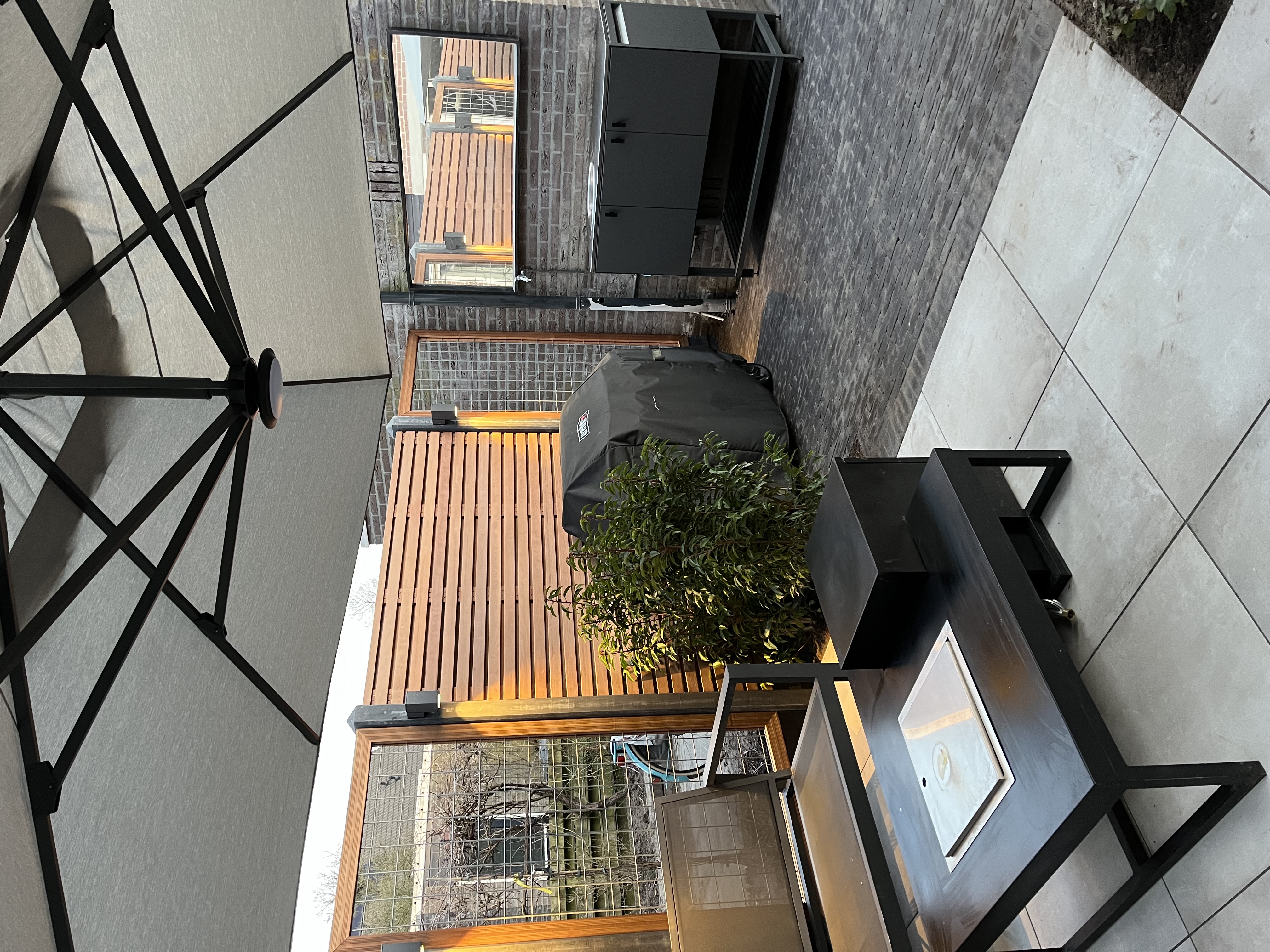 Modern terras met houten vlonder, plantenbak en buitenkeuken